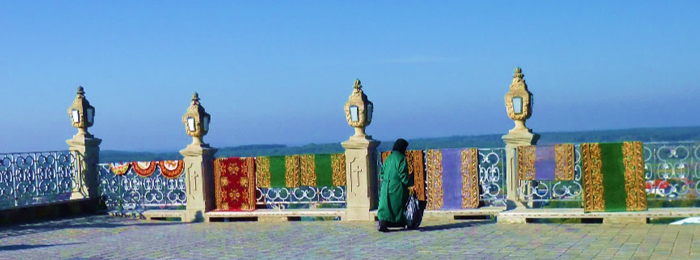 image of person cleaning colorful rugs at Pochaev